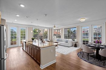 A kitchen with a center island next to a living room with a couch and a table